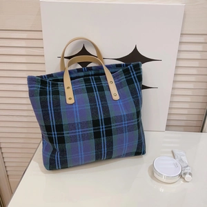 Vintage plaid tote bag in blue and black fabric with brown leather handles on desk