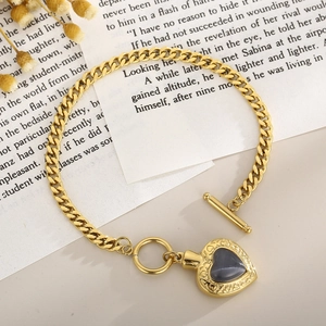 Détail d'un bracelet doré avec cœur en opale, motifs en relief et fermoir à bascule