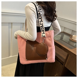 Detail of canvas tote bag with pink stitching, brown leather pocket and round pouch charm