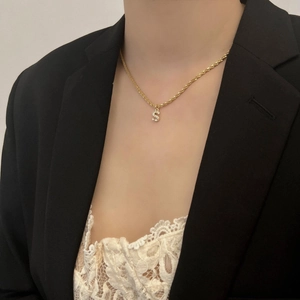 Vue détaillée du collier chaîne dorée avec pendentif lettre S serti de pierres brillantes