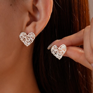 Silver openwork heart stud earrings with zircon mesh design shown on model ear