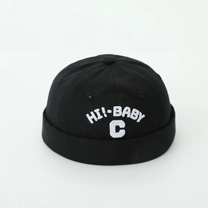 Close-up of black brimless docker hat featuring white 'HI!-BABY' letter embroidery texture