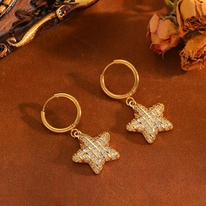 Star-shaped gold earrings with sparkling zircon stones on a vintage textured background