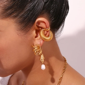 Close-up of gold geometric earrings set with pearl charms and a textured hoop on model