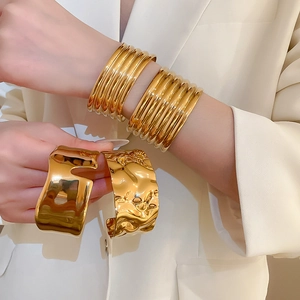 Golden wide open cuff bracelet set with textured and wavy finish on a fashion model