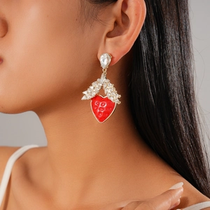 Detail of elegant red heart earrings with crystals worn by a model on a grey background