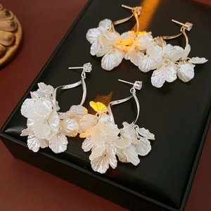 Detail von eleganten weißen Muschelblüten Ohrringen mit Zirkonia auf schwarzem Lederetui