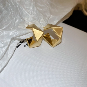 Macro shot of geometric heart earrings with matte brushed finish and polished gold edges