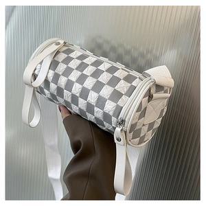 Close-up of grey and white checkerboard cylinder bag with pleated texture and silver zipper