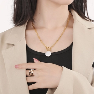 Detailed view of gold baroque shell necklace and ring set worn on professional model