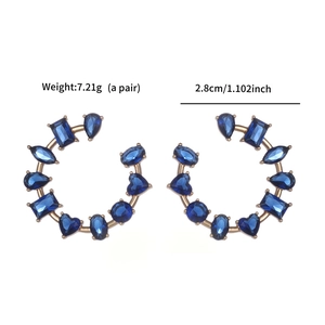 Detail view of C-shaped gold earrings with dark blue zircons showing 2.8cm diameter size
