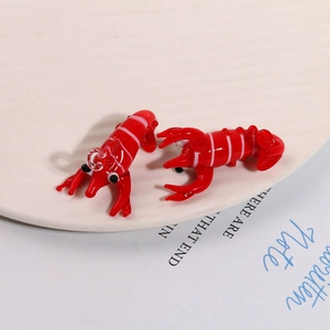 Macro shot of two creative red glass lobster charms with hanging loops for DIY jewelry