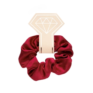 Detail of dark red satin scrunchie displayed on a diamond-shaped beige gift card
