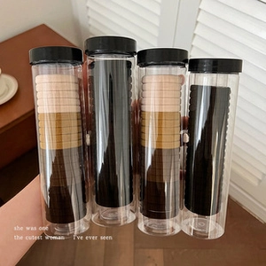 Detail of four cylindrical packs of neutral toned elastic hair ties held by hand
