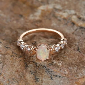 Macro shot of rose gold celestial ring with opal stone and moon details on rock