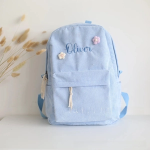 Detail of personalized Oliver name embroidery with floral accents on blue corduroy backpack