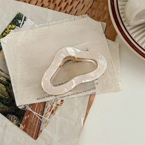 Iridescent white acetate hair claw clip with shell luster on aesthetic vintage background