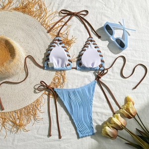 Flat lay of light blue textured bikini with brown side ties and beach accessories