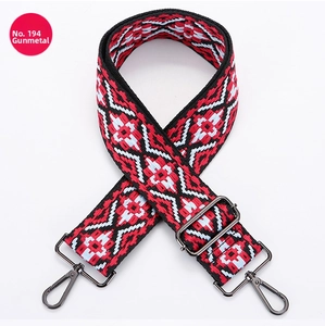 Macro detail of red and black geometric woven canvas bag strap with gunmetal buckles