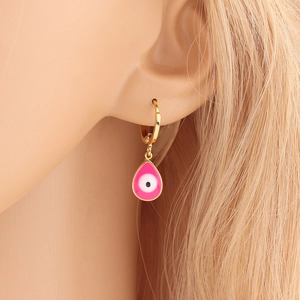 Close-up of a gold hoop earring with a pink enamel Evil Eye teardrop charm on model