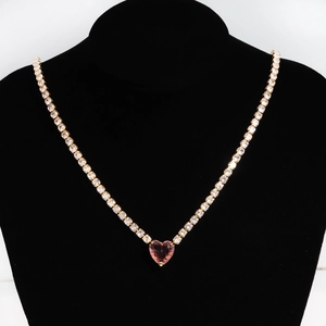 Detail of gold tennis chain with a sparkling pink heart-shaped zircon pendant