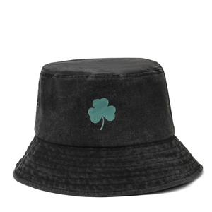 Washed black cotton bucket hat featuring a green shamrock embroidery and stitched brim