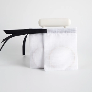 Detail view of translucent white drawstring pouch with elegant black ribbon closure