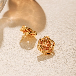 Macro detail of French irregular golden flower stud earrings with twisted metal texture