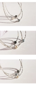 Close-up of triple-layered silver bead chain necklace with white and grey pearls