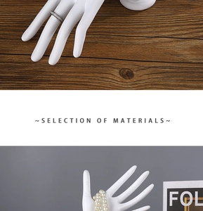 Close-up of white matte resin hand-shaped stand displaying rings and pearl bracelets