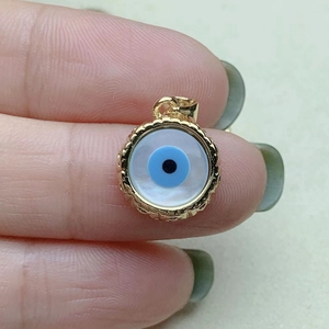 Detailed close-up of a gold-rimmed evil eye charm with blue details and mother of pearl