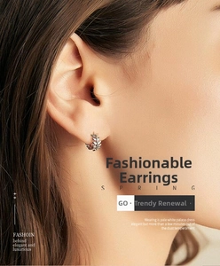 Close-up of silver leaf hoop earring worn by a model showcasing minimalist style and detail