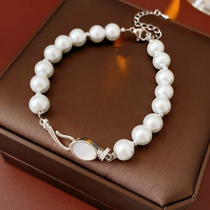 Macro detail of elegant pearl bracelet featuring zirconia inlay and silver shell clasp