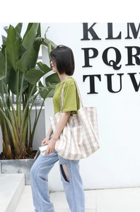 Lifestyle view of a large striped canvas tote bag styled with a casual summer outfit
