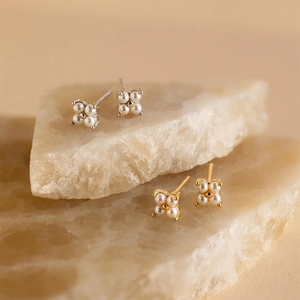 Elegant four-petal pearl flower earrings in gold and silver settings on stone
