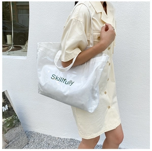 Detail shot of a clear PVC tote bag with white canvas lining and Skillfully text