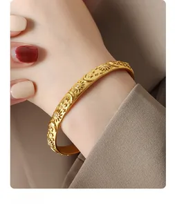 Macro view of gold bangle with celestial sun and moon relief worn over suit cuff