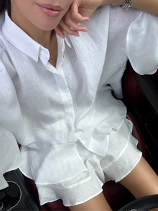 Gros plan sur l'ensemble chemise et short blanc en lin sur fond de cuir rouge