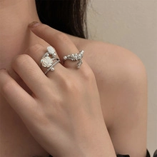 Detailed shot of silver rings featuring a white rose and a pearl diamond band