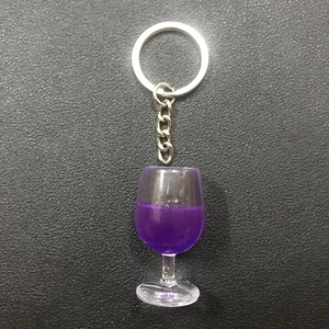 Creative resin wine glass keychain with purple liquid on black leather background