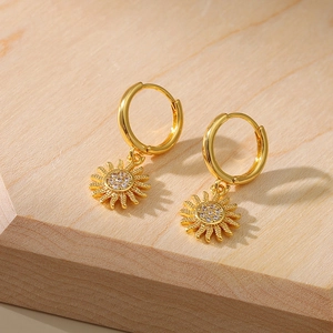 Detail of sunflower drop earrings with micro-inlaid zircons on a wooden display stand