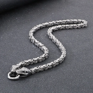 Macro shot of silver Byzantine chain with detailed double snake heads holding a ring
