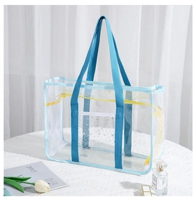 Detailansicht der transparenten PVC-Reisetasche mit blauem Rand und Mesh auf weißem Tisch