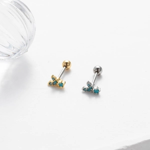 Macro shot of gold and silver screw-back cartilage earrings with turquoise blue stones