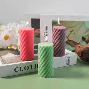 Detail showing spiral texture of cylindrical pastel scented candles with burning wicks