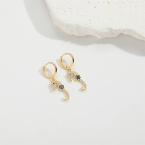 Macro detail of golden seahorse earrings with white pavé stones and blue floral gems