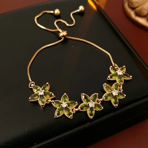 Nahaufnahme des Zirkon-Sternblumen-Armbands mit grünen Steinen und goldenen Details