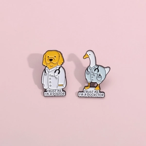 Close-up of enamel pins featuring a dog and duck with humorous medical puns on pink backdrop