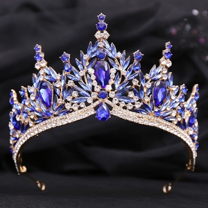Close-up of golden bridal crown with deep blue and clear crystals on dark fabric