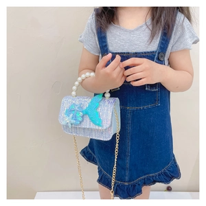 Detail of girls' tweed pearl handbag with sequins and mermaid tail on denim dress